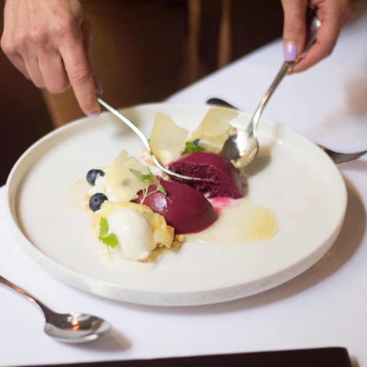 Dolce al piatto con quenelle di sorbetto ai frutti rossi, mirtilli e scaglie di cioccolato bianco