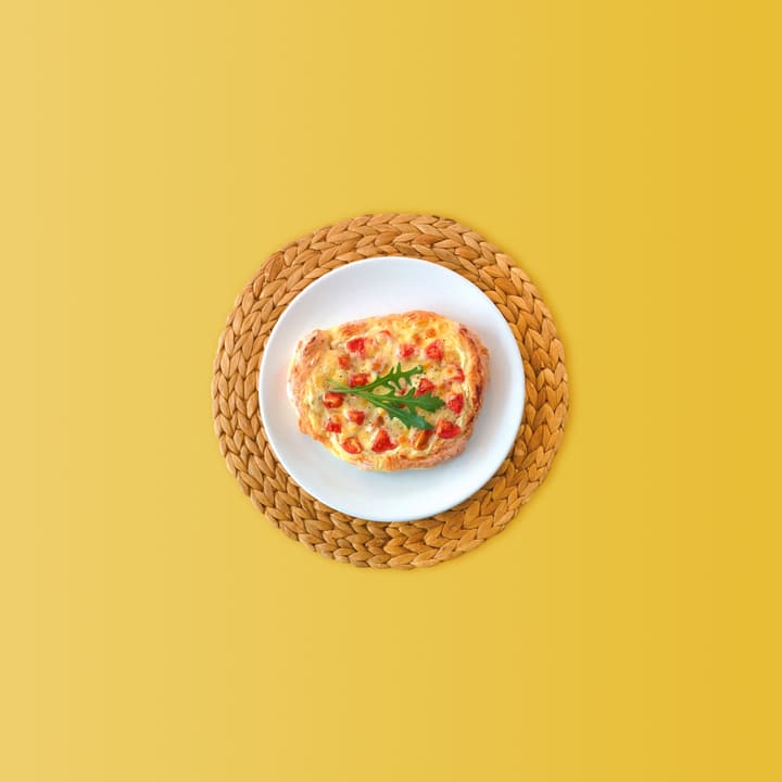 Bruschetta con formaggio filante, pomodoro e rucola su un piatto bianco appoggiato a una stuoia intrecciata